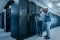 The picture shows two engineers in a modern data centre, working with their computer 